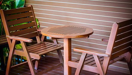 How should wooden tables and chairs be cleaned of dirt?